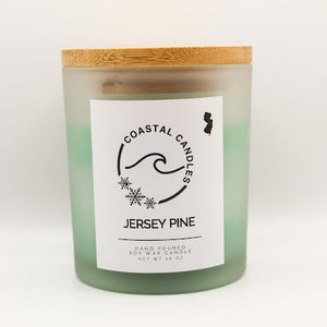 Peut inclure: Un bocal en verre givré avec un couvercle en bambou. La bougie est verte et porte une étiquette blanche sur laquelle est inscrit "Coastal Candles" avec une vague et des flocons de neige. L'étiquette indique également "Jersey Pine" et "Bougie en cire de soja coulée à la main, Poids net 10 oz."