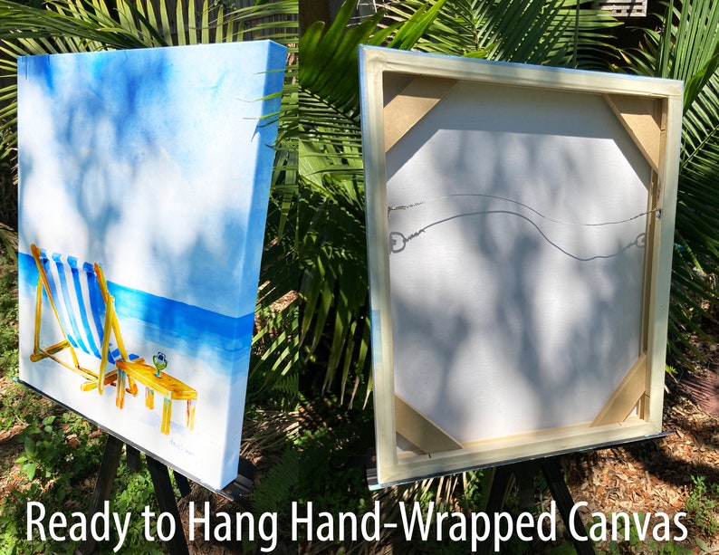 May include: A hand-painted canvas print of a beach scene with two blue and white striped beach chairs, a table with a drink, and a blue sky with white clouds. The canvas is wrapped around a wooden frame and is ready to hang.