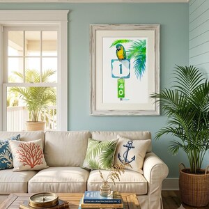 Bright coastal living room decor mockup featuring a framed tropical watercolor print by David K Jones titled A Parrot Looks at 40. The artwork hangs blue wall, creating a beach house aesthetic.