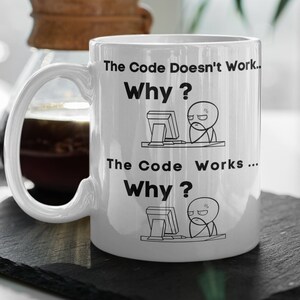 Può includere: Una tazza in ceramica bianca con un design nero. La tazza presenta un personaggio dei cartoni animati al computer con il testo "The Code Doesn't Work... Why?" e "The Code Works... Why?"