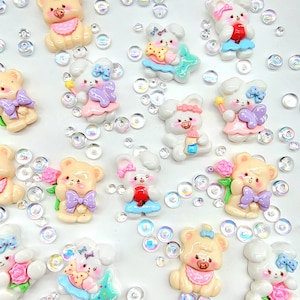 May include: Assortment of 12 white and cream colored resin bear and bunny charms with pastel pink, blue, and purple accents. The charms feature bows, flowers, and other cute details.
