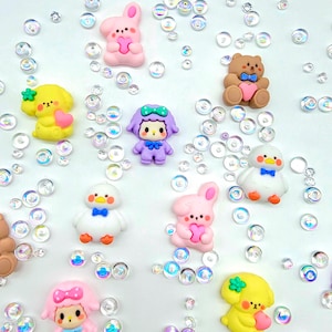 May include: Assortment of colorful, cartoon animal charms with hearts. The charms are made of polymer clay and feature a variety of animals, including a bunny, a bear, a lamb, a chick, and a dog. The charms are perfect for adding a touch of whimsy to any project.
