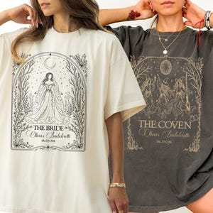 May include: Two oversized t-shirts. The cream shirt features a black line-art graphic of a bride in a forest frame with text reading THE BRIDE, Olivia's Bachelorette, SALEM, MA. The charcoal shirt shows three witches with text THE COVEN, Olivia's Bachelorette, SALEM, MA.