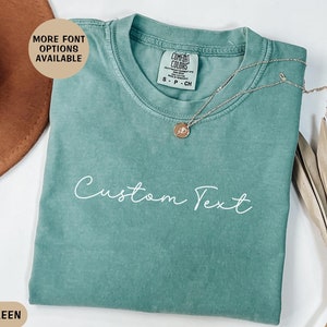 May include: Light green t-shirt with the text "Custom Text" in white. The shirt is made of a soft, comfortable material and has a relaxed fit.