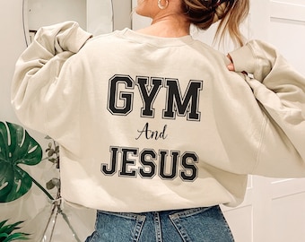 May include: A beige sweatshirt with the text "GYM And JESUS" printed on the back in black.