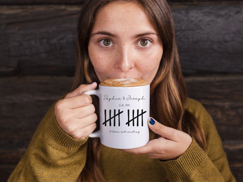 May include: White ceramic mug with black text and markings. The text reads "Sophie & Joseph Est. 2014" and "10 Years and counting".
