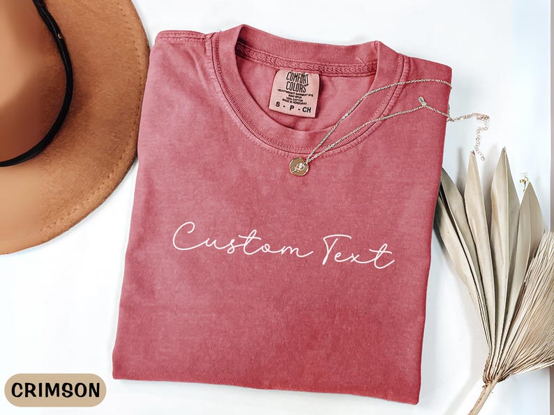 May include: Crimson red t-shirt with a white "Custom Text" design. The shirt is made of a soft, comfortable fabric and has a relaxed fit.