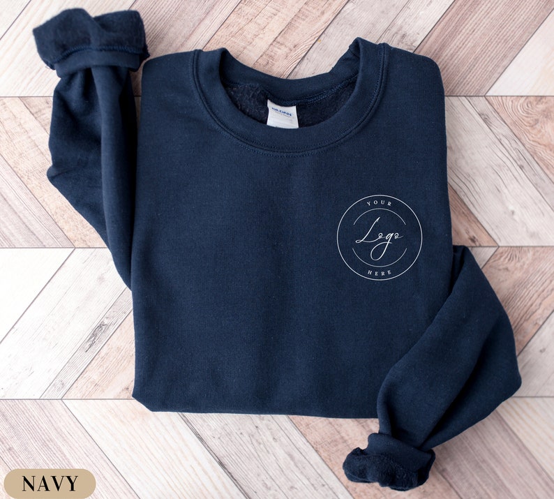 May include: A navy blue sweatshirt with a white circle on the front that says "Your Logo Here".