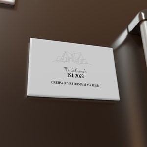 May include: White square magnet with a house illustration and the text "The Johnson's Est. 2023 Courtesy of Your Friends at NYY Realty" on a brown refrigerator.