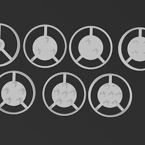 Puede incluir: Siete objetos circulares grises con un diseño similar a una rueda están dispuestos sobre un fondo gris oscuro. Cada objeto tiene un círculo central con un patrón texturizado y radios que se extienden hacia el anillo exterior. Los objetos varían.