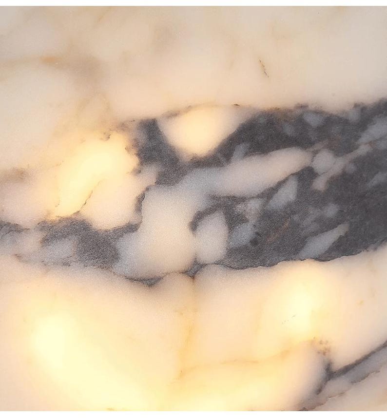 May include: Close-up of a white marble surface with gray veining. The surface is smooth and polished, with a subtle sheen.