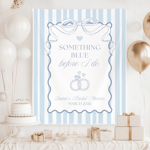 May include: A blue and white striped banner with the text "Something Blue before I do" and wedding ring graphics. The banner is decorated with a bow and heart. The banner is for Emma's Bridal Shower, March 2026.