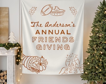 Könnte beinhalten: Cremefarbene Tapisserie mit braunen Illustrationen und Text. Der Text lautet „The Anderson's ANNUAL FRIENDS GIVING“. Zu den Illustrationen gehören ein Football, ein Kuchen, ein Füllhorn und Sektgläser. Ein Weihnachtsbaum und ein Kamin befinden sich im Hintergrund.