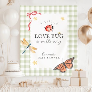 May include: A baby shower sign with the text "A Little Love Bug is on the Way" and "Emma's Baby Shower". The sign features illustrations of a ladybug, dragonfly, butterfly, and flowers. The background is a green and white gingham pattern.