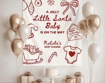 May include: A Christmas-themed baby shower setup featuring a banner with the text "A Jolly Little Santa Baby is on the Way." The scene includes gold and white balloons, wrapped gifts, a cake, and festive illustrations.