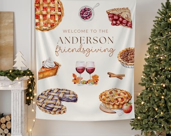 May include: A cream-colored Friendsgiving tapestry featuring watercolor illustrations of various pies, wine glasses, and fall foliage. The text "WELCOME TO THE ANDERSON friendsgiving" is displayed in brown script. A festive decoration for a holiday gathering.