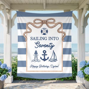 May include: A rectangular fabric banner featuring a blue and white horizontal striped background. The center displays a white panel framed by a rope border, with the text "SAILING INTO Seventy" and "Happy Birthday, Dylan!" alongside nautical icons.