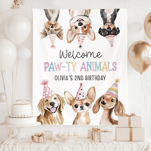 Può includere: Un banner bianco con la scritta "Welcome PAW-TY ANIMALS" e "OLIVIA'S 2ND BIRTHDAY". Il banner presenta illustrazioni di cani con cappelli da festa. Palloncini e una torta sono visibili sullo sfondo.