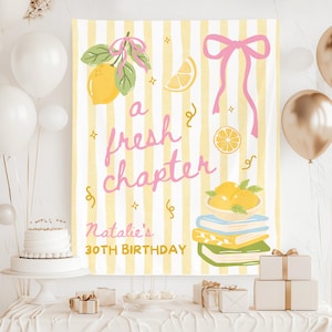 May include: A party backdrop with a yellow and white striped background, featuring lemons, a pink bow, and the text "a fresh chapter." The text "Natalie's 30th Birthday" is also displayed. White and gold balloons, a cake, and gifts are in the foreground.