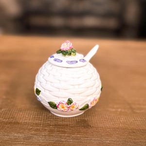 May include: A white ceramic mug with a black handle and the text "But First, Coffee" in a handwritten style. The mug is on a white surface. The mug is approximately 4 inches tall.