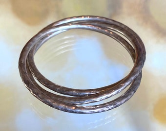May include: Three silver bangles with a hammered texture.