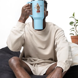 May include: A light blue tumbler with a handle and a straw. The tumbler features a graphic of a woman with long blonde hair and the text "Love you forever". The tumbler is held by a person.