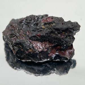 May include: A dark gray and purple rock with a rough, uneven surface.
