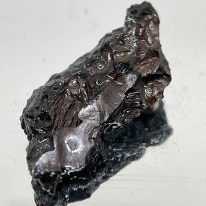 May include: A dark gray, rough, and irregularly shaped rock with a metallic sheen.
