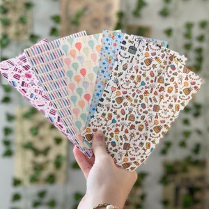 May include: A set of six colorful patterned paper sheets with birthday themes. The patterns include balloons, candles, stars, and confetti.