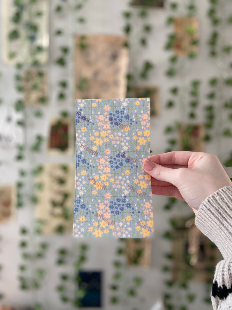 Pu&ograve; includere: Un tessuto blu e bianco con un motivo floreale. Il tessuto &egrave; ricoperto di piccoli fiori gialli, rosa e blu.