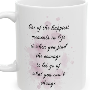 Puede incluir: Taza de cerámica blanca con asa, con la cita "One of the happiest moments in life is when you find the courage to let go of what you can't change" en escritura negra sobre un diseño de acuarela rosa.