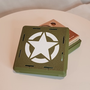 May include: A green plastic case with a white star in a circle design. The case is open and has a brown cardboard box inside.