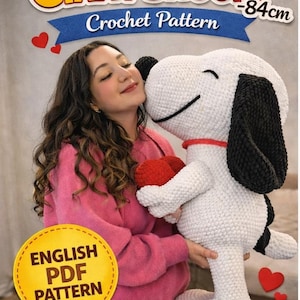 May include: A crochet pattern for a giant Snoopy doll, approximately 84cm tall, is shown. The image features a woman holding the finished white and black Snoopy doll, with a red heart. The pattern is an English PDF.