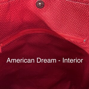 K&ouml;nnte beinhalten: Das Innere einer roten und wei&szlig;en Tragetasche mit einer Rei&szlig;verschlusstasche. Der Text "American Dream - Interior" ist auf den Stoff gedruckt.