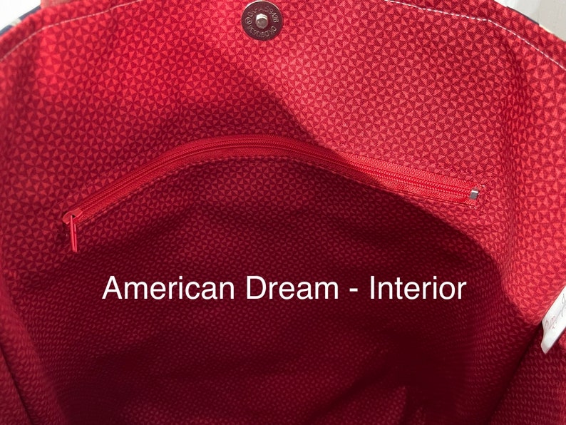 K&ouml;nnte beinhalten: Das Innere einer roten und wei&szlig;en Tragetasche mit einer Rei&szlig;verschlusstasche. Der Text "American Dream - Interior" ist auf den Stoff gedruckt.