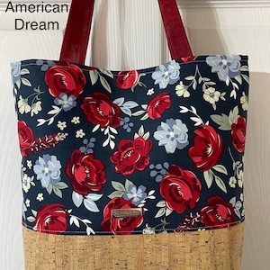 K&ouml;nnte beinhalten: Eine marineblaue Tragetasche mit rotem und wei&szlig;em Blumendruck. Die Tasche hat einen Korkboden und rote Henkel. Die Tasche hat ein kleines braunes Etikett mit der Aufschrift "handgefertigt".