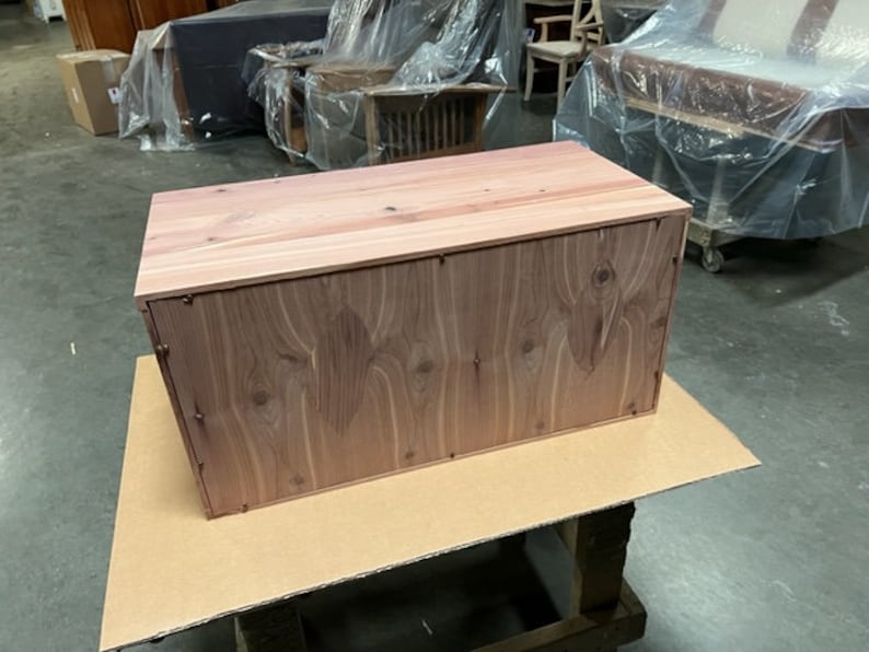 May include: A wooden storage box with a natural wood finish. The box has a rectangular shape and is made of solid wood.