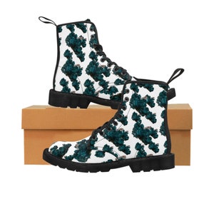 May include: Black and white boots with a teal and white geometric pattern. The boots have black laces and a black sole.