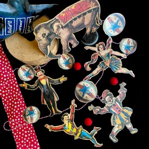 May include: A colorful garland with a circus theme. It features a red, white, and blue elephant, a clown, a ringmaster, and stars. The garland is perfect for a party or celebration.