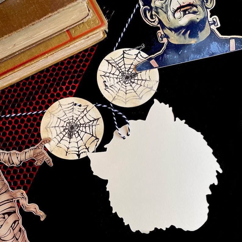 May include: Halloween themed gift tags with a spiderweb design, a blank tag shaped like a wolf's head, and a vintage illustration of Frankenstein's monster.