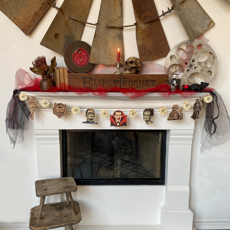 May include: A white fireplace mantel decorated with a black and white Halloween garland featuring various monster characters. The garland is strung with black and white ribbon and hangs above a black fireplace.