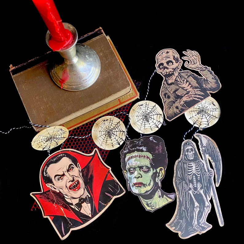 May include: A Halloween garland with a black and white spiderweb design, a black and white illustration of a vampire, a black and white illustration of Frankenstein's monster, a black and white illustration of a skeleton, and a black and white illustration of a zombie.