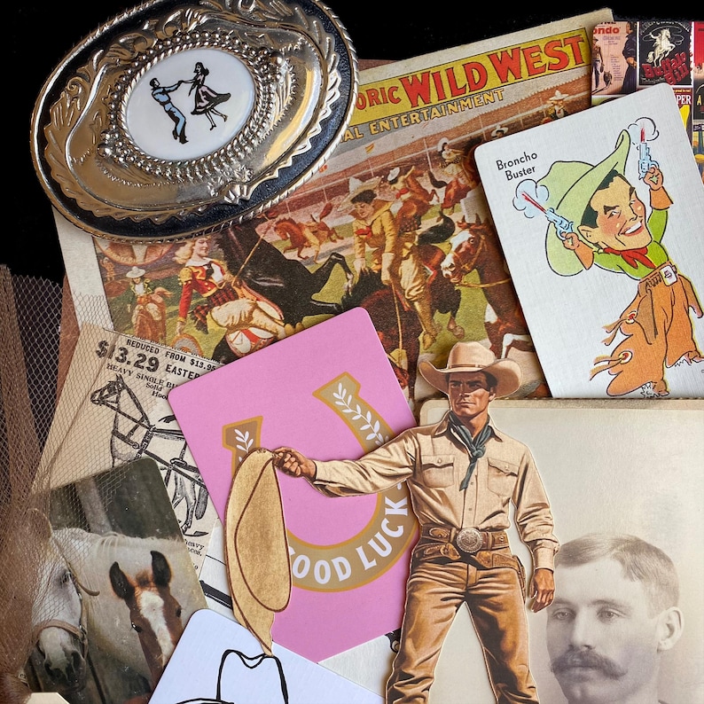 May include: A collection of vintage Western-themed items. Includes a silver belt buckle with a dancing couple, playing cards, a pink card with "GOOD LUCK" text, and a cowboy cutout. The items are arranged on a black surface.