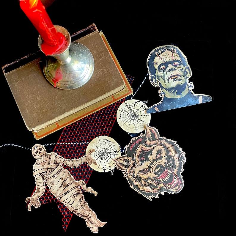 May include: Halloween party decorations featuring a string of paper cutouts with images of a werewolf, Frankenstein's monster, a mummy, and spiderwebs.