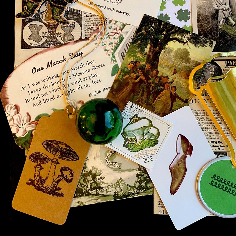 May include: A collage of vintage ephemera with a green glass ball, a brown paper tag with a mushroom illustration, a postage stamp with a mushroom illustration, a postcard with a group of children dancing under a tree, and a gold-colored metal object.