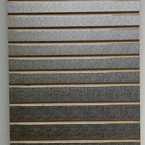 May include: A silver and gold textured wall panel with horizontal grooves. The panel is made of a material that resembles metal.