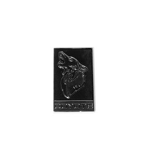 May include: Black metal pin with a wolf howling at the moon. The pin has the word "Coyote" written below the wolf.