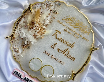 May include: White resin ring dish with gold accents and a floral design. The dish has two ring holders and the text "And we created you in pairs Quran (78:8) Raeesah & Adam 20th April 2025" in gold lettering.