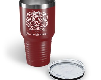 May include: A red stainless steel tumbler with a white inscription that reads "Fresh Sarcasm Served Daily You're Welcome". The tumbler has a black lid with a clear plastic insert.
