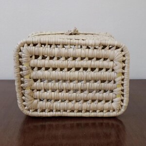 May include: A rectangular woven basket made of natural straw with a light beige color. The basket has a woven pattern and a slightly raised rim.